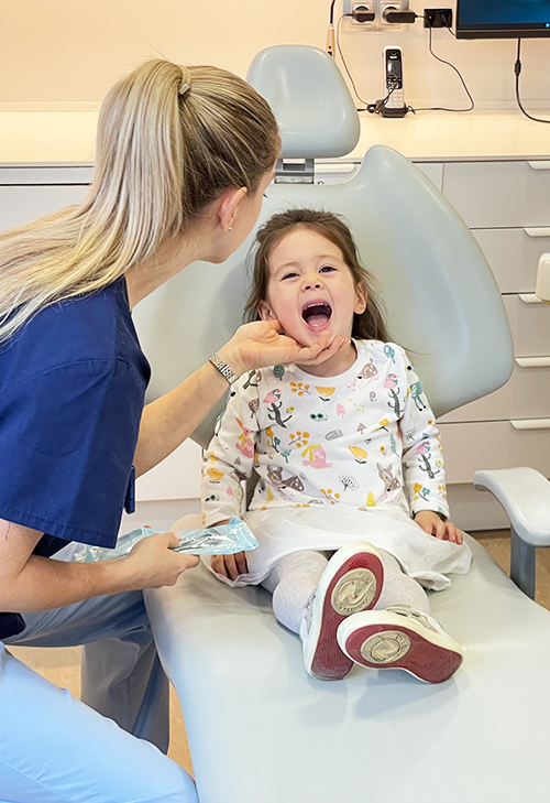 Una dentista mira los dientes de una niña en una clínica dental moderna.